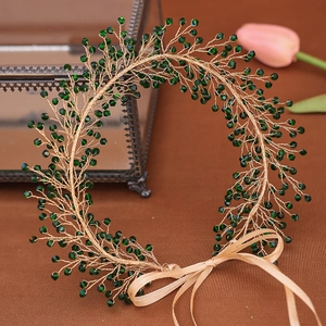 Detail of handmade gold wire headband with green crystal beads and a silk ribbon bow