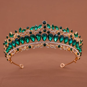 Detailed macro view of vintage gold crown featuring teardrop emerald stones and rhinestones