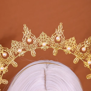 Close-up of golden hollowed crown headband with pearls on a vintage white wig