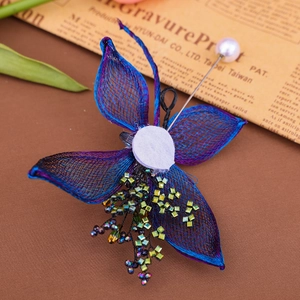 Macro view of blue mesh flower brooch with colorful rhinestones and pearl pin detail