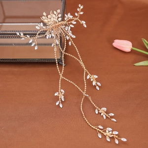 Detailed view of handmade bridal hair comb with gold leaves, white beads, and tassels