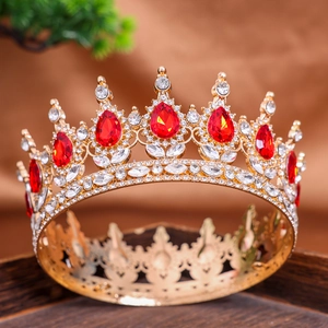 Detailed view of golden crown featuring large red teardrop stones and white rhinestones