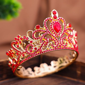 Dettaglio corona dorata con strass rossi, motivi a cuore traforati e rubini da sposa