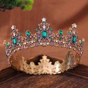 Luxurious vintage crown with emerald green stones and multicolor crystals on gold base