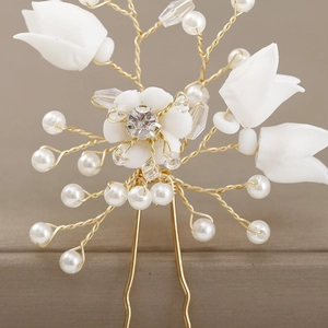 Detailed close-up of golden bridal U-shaped hair pin with clay flowers and faux pearls