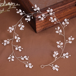 Elegant handcrafted pearl bridal headband with silver wire vines on brown velvet background