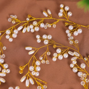 Détails d'un accessoire de cheveux mariée fait main avec perles blanches et fil doré