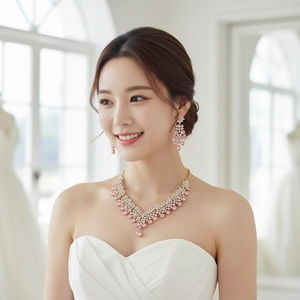 Close-up of bridal jewelry set with pink crystal floral necklace and drop earrings
