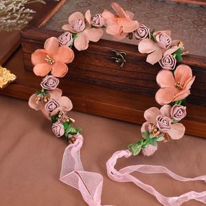 Ghirlanda di fiori con rose in chiffon rosa e foglie verdi su sfondo di legno vintage