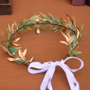 Detail of green leaf tiara with golden pendant and adjustable white silk ribbon