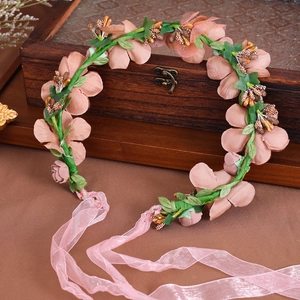 Dettaglio della fascia floreale vintage con fiori in tessuto rosa e foglie realistiche