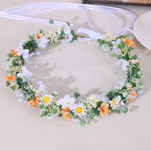 Detail of floral bridal headband with white daisies, green leaves, and satin ribbon