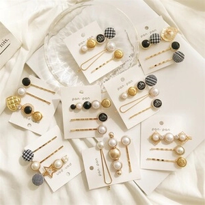 Detail of elegant hair clip set with pearls and gold star charms on a white display card