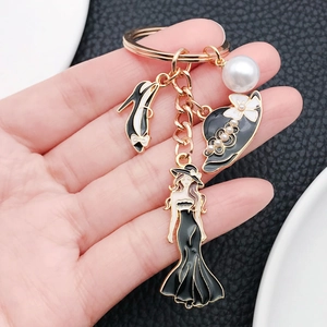 Porte-clés doré élégant avec robe noire, chapeau, talons hauts et perle blanche