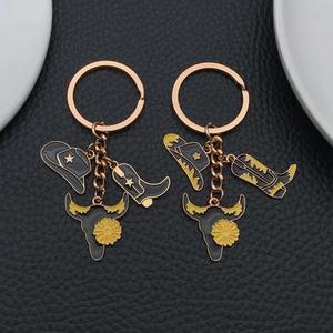 Western cowboy keychain set with black hat, boots, and bull skull on leather background
