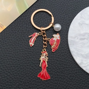 Detail of red enamel high heels, hat, and dress charms with pearl on golden keychain