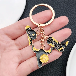 Western style enamel keychain with cowboy hat, bull skull, and boot charms in rose gold