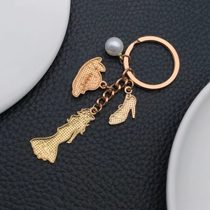 Detailed view of golden fashion keychain with pearl, dress, hat, and high heel charms