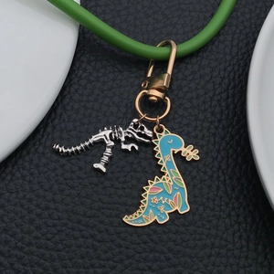 Detail of silver dinosaur skeleton and blue enamel cartoon charm on golden keychain