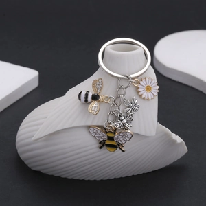Enamel bee and daisy keychain set with rhinestones on white ceramic stand