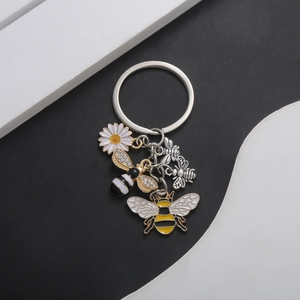 Detailed view of bee and daisy pendants on a polished silver alloy keychain