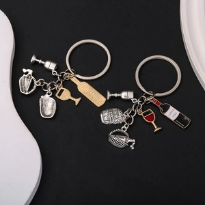 Detailed view of metal wine bottle, glass, and barrel pendants on a keychain charm