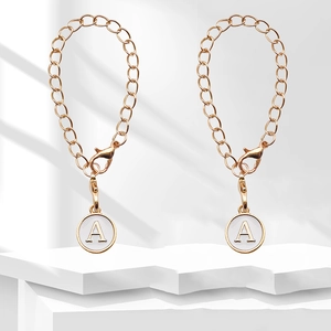Detail view of a gold chain with white enamel letter A pendant and lobster clasp