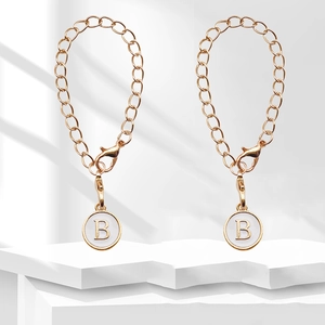 Detailed view of golden metal chains with letter B pendants and lobster clasps