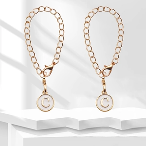 Close-up of golden chain with lobster clasp and white enamel pendant with letter C