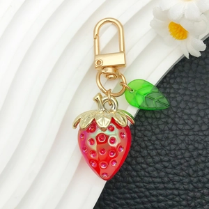 Close-up of strawberry pendant with sparkling rhinestones and golden D-ring hardware