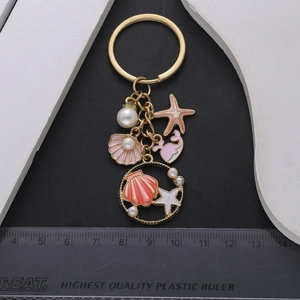 Pink starfish and whale ocean theme metal keychain with pearls on black background