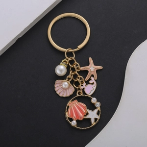 Pink pearl starfish and whale tail keychain in gold metal with enamel ocean charms