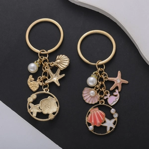 Detail of pink enamel whale and starfish charms on a gold-plated ocean-themed keychain
