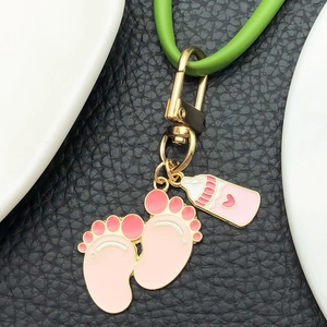Pink baby feet and milk bottle keychain with golden lobster clasp on black leather