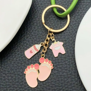 Cute pink baby bottle and footprint enamel charms on a gold keychain with black leather base