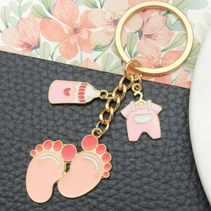 Golden keychain with pink enamel baby bottle, footprint, and jumpsuit pendants