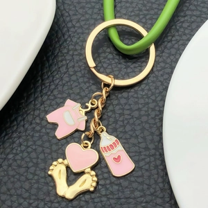 Porte-clés doré avec body bébé en émail rose, cœur avec empreintes et petit biberon mignon