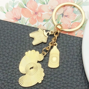 Cute golden baby bottle and clothes charms on a textured metallic keychain accessory