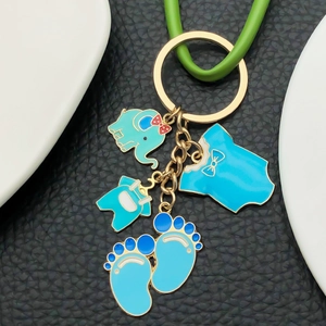 Golden elephant baby shower keychain with blue enamel charms on a black background