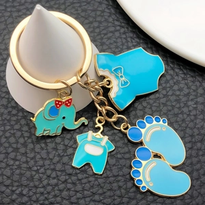 Close-up of blue enamel baby charms featuring elephant and feet on a gold keychain