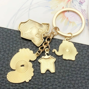 Golden elephant and bottle charm keychain with textured metal pendants on black leather