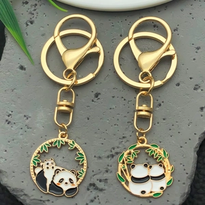 Close-up of golden metal panda keychains with black and white enamel and bamboo leaf charms