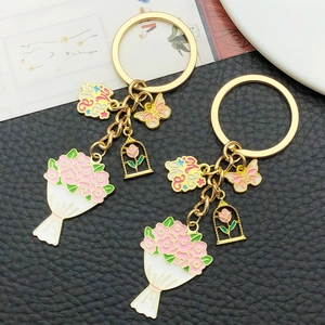 Détail du porte-clés doré avec bouquet rose, papillon émaillé et pendentif Mama