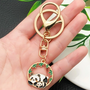 Golden panda keychain with enamel panda and bamboo pendant shown in hand detail