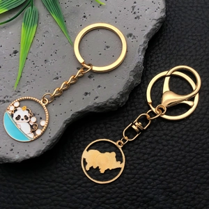 Close-up of golden metal panda keychains with enamel finish on a premium textured backdrop