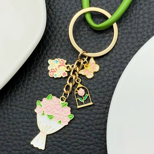 Détail d'un porte-clés doré Mama avec fleurs et papillon rose sur cuir noir élégant