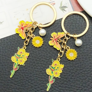 Close-up of yellow sunflower and butterfly enamel pendant on golden keychain