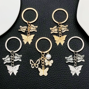 Detailed close-up of hollow butterfly keychains with rhinestones and faux pearls on leather