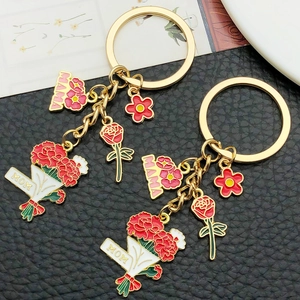 Close-up of golden enamel carnation and rose pendants for Mother's Day keychain