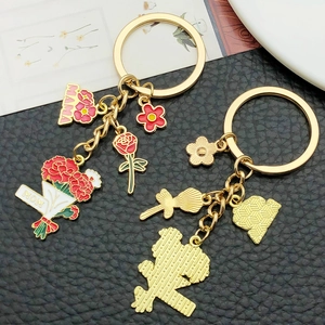 Golden keychain set with red carnation MAMA flower charms on black leather background
